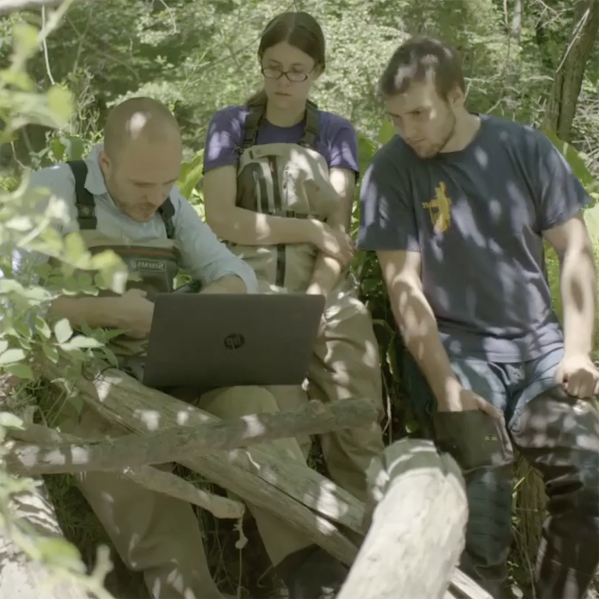 Photo of a faculty member and two students studying water near a creek on Eden Hall Campus